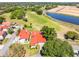Aerial view showcasing the beautiful red tile roof, lush trees and landscaping around the home near a pond and golf course at 7016 Village Dr, Lake Wales, FL 33898