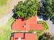 Aerial view of a home with a red tile roof, surrounded by lush greenery and manicured lawns at 7016 Village Dr, Lake Wales, FL 33898