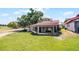 A beautifully landscaped backyard featuring lush green grass, mature trees, and a view of the golf course at 7016 Village Dr, Lake Wales, FL 33898