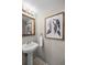 Cozy bathroom features a pedestal sink, decorative mirror, and stylish botanical wall art, enhancing its appeal at 7016 Village Dr, Lake Wales, FL 33898