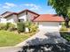 Charming single-story villa with a two-car garage, red tile roof, and well-manicured landscaping at 7016 Village Dr, Lake Wales, FL 33898
