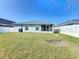 A large, well-maintained backyard with a gray house and white fence under a clear blue sky at 895 Orleans Dr, Eagle Lake, FL 33839