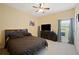 Cozy bedroom with a dark wood dresser, flat screen TV, and a large window at 9461 Redhawk Bend Ln, Lakeland, FL 33810