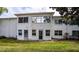 A view of the property's green backyard and white stucco exterior with multiple windows and doors at 1100 Martinique Dr # 106, Winter Haven, FL 33884