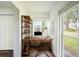 Bright home office featuring a rustic wood desk, metal chair, and a shelving unit with books and decorations at 1100 Martinique Dr # 106, Winter Haven, FL 33884