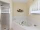 Relaxing bathroom with a jetted tub, a glass-enclosed shower, and a decorative fish-themed accent at 123 Morning Glory Cir, Winter Haven, FL 33884