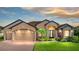 Charming tan home features a three-car garage, beautiful landscaping, brick driveway and walkway at 1336 Oakmont Dr, Winter Haven, FL 33884