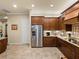 Kitchen featuring stainless steel refrigerator, granite countertops, tile floors, and wood cabinets at 1336 Oakmont Dr, Winter Haven, FL 33884