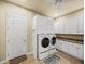 Well-lit laundry room with white cabinetry, countertop, washer, dryer, tile flooring, and ceiling fan at 1336 Oakmont Dr, Winter Haven, FL 33884