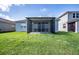 Lush backyard featuring a screened-in patio, green grass, and a view of neighboring houses at 153 Summershore Dr, Auburndale, FL 33823