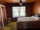 Modest bedroom features wood paneled walls, window, ceiling fan, and neutral flooring at 201 Cleveland Avenue, Winter Haven, FL 33881