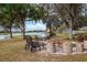 Outdoor seating around a cozy brick fire pit, complemented by a serene lake view and picturesque trees at 20143 Sunset Landing Ave, Groveland, FL 34736