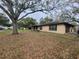 A single-story brick home with an attached garage, surrounded by lush greenery and mature trees at 2016 Amesbury Dr, Auburndale, FL 33823