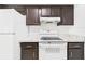 Bright kitchen featuring white appliances, white backsplash, and dark brown cabinets at 2434 Mill Run Blvd, Kissimmee, FL 34744