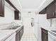 Bright kitchen featuring stainless steel sink, marble-like countertop, white appliances, and dark cabinets at 2434 Mill Run Blvd, Kissimmee, FL 34744