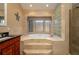 Bright bathroom featuring a glass block window, walk-in shower and soaking tub at 2506 Partridge Dr, Winter Haven, FL 33884