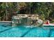 A close view of screened pool with rock waterfall feature surrounded by lush greenery at 2506 Partridge Dr, Winter Haven, FL 33884