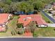 An aerial view of a single-story home with a red roof, a red driveway, and lush landscaping near a pond at 2637 Sunburst Ct, Lake Wales, FL 33898