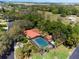 An aerial view of a single-story home with a red tile roof and an enclosed pool in a lush, green setting at 2637 Sunburst Ct, Lake Wales, FL 33898