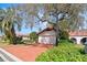 Charming single-story home with a red tile roof, red driveway, mature trees, and lush landscaping at 2637 Sunburst Ct, Lake Wales, FL 33898