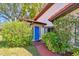 Charming home entrance with a vibrant blue door surrounded by lush, mature greenery and a red brick walkway at 2637 Sunburst Ct, Lake Wales, FL 33898