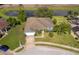 Aerial shot of landscaped property with pond, mature palms, lawn, and blue single story home at 295 E White Ibis Ln, Winter Haven, FL 33884