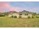 Image shows the rear exterior of the house surrounded by grassy yard and a blue and pink sky at 3065 E Central Ave, Bartow, FL 33830