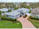 Aerial view of blue home with lush landscaping and a brick driveway at 3416 Grenville Dr, Winter Haven, FL 33884