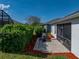 Home's backyard featuring a brick patio, green shrubs, and a covered grill at 3686 Plymouth Dr, Winter Haven, FL 33884