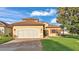 Charming single-Gathering home with a terracotta roof, lush lawn, and a paved driveway leading to an attached garage at 369 Villa Sorrento Cir, Haines City, FL 33844