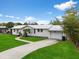 A well-maintained single-story home showcasing a white exterior, lovely landscaping, and an attached garage at 4024 Canal Rd, Lake Wales, FL 33898