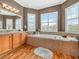 Bright bathroom with a soaking tub, tiled surround, and double windows at 4073 Sable Loop Dr, Lake Wales, FL 33859