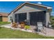 The enclosed patio features wicker furniture and a grill with brick flooring and views of the backyard at 5304 Nicklaus Dr, Winter Haven, FL 33884