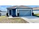 Single-story home featuring blue siding, a two-car garage, and a well-maintained lawn at 663 Lucerne Blvd, Winter Haven, FL 33881