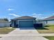 Inviting single-story home with a two-car garage, well-manicured lawn, and beautiful blue siding at 663 Lucerne Blvd, Winter Haven, FL 33881