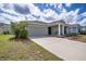 Welcoming one-story home with attached garage, green lawn, manicured shrubbery, and covered entry at 708 Simone Ct, Haines City, FL 33844