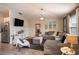 A well-lit living room featuring a large grey sectional, a modern coffee table, and a stainless steel fridge at 708 Simone Ct, Haines City, FL 33844
