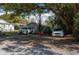 Residential scene with two vehicles parked in a shaded area, complemented by lush greenery and a building in the background at 750 Avenue O Sw, Winter Haven, FL 33880