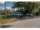 View of a residential street with a house, driveway, and two cars parked under the shade of a large tree at 750 Avenue O Sw, Winter Haven, FL 33880