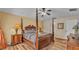 A well-lit bedroom featuring a four-poster bed, wood floors, and ceiling fan at 7759 Basnett Cir, Kissimmee, FL 34747