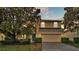 Inviting home exterior featuring a well-maintained lawn, mature tree, and a two-car garage for convenience at 7759 Basnett Cir, Kissimmee, FL 34747
