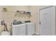 Bright laundry room featuring a washer, dryer, and a shelf for supplies at 7759 Basnett Cir, Kissimmee, FL 34747