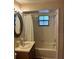 Cozy bathroom featuring a shower-tub combo, vanity with an ornate mirror, and natural light at 907 Van Dr, Auburndale, FL 33823