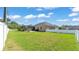 Large backyard with green lawn, fenced perimeter, screened enclosure, and a glimpse of neighboring homes at 9502 Waterford Oaks Blvd, Winter Haven, FL 33884