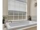 Close-up of a luxurious bathtub with a large window, neutral walls, and tile surround at 9502 Waterford Oaks Blvd, Winter Haven, FL 33884
