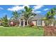 Stunning home featuring manicured lawn, mature palm trees and lush landscaping around the foundation at 9502 Waterford Oaks Blvd, Winter Haven, FL 33884