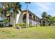 Condo exterior featuring arched windows, manicured landscaping, and mature palm trees at 1104 Country Club Dr # A-4, Lake Wales, FL 33898