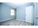Comfortable bedroom with light blue walls, laminate floors, a window, and a white door at 1328 3Rd Ne St, Winter Haven, FL 33881
