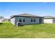 A gray single-story home featuring a well-maintained lawn and a sliding glass door leading to the backyard at 1340 Oak Valley Drive, Auburndale, FL 33823