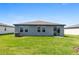 A gray single-story home featuring a well-maintained lawn and a sliding glass door leading to the backyard at 1340 Oak Valley Drive, Auburndale, FL 33823